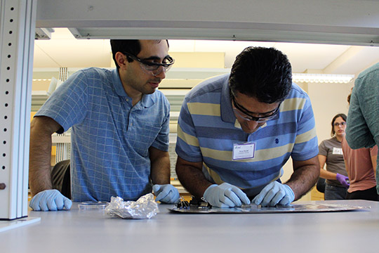 Hooman watches Reza align the cover slip on his chip.