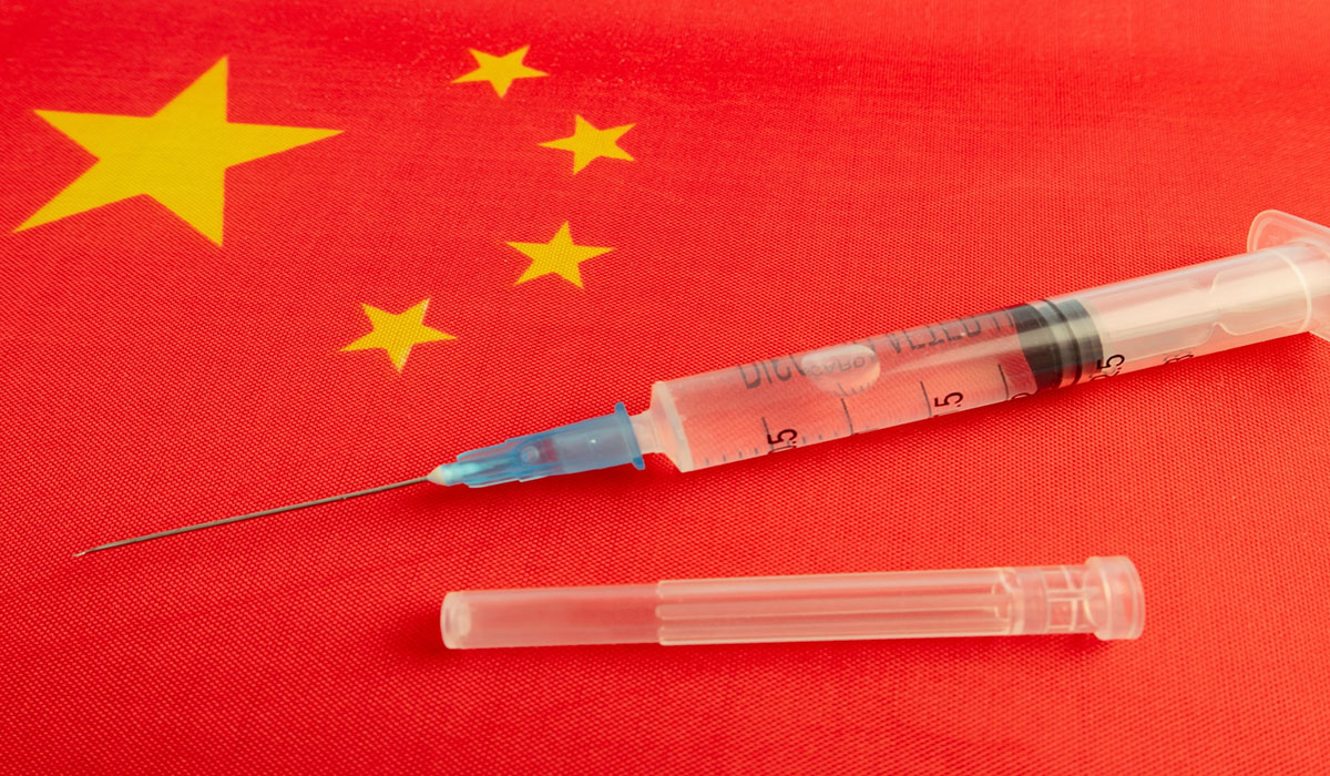Chinese flag with vaccine needles sitting on top of it.