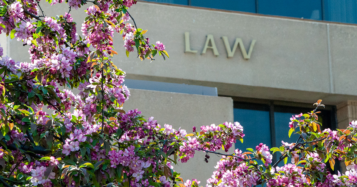 Colorful spring blooms frame the words "Law" on the outside of Green Hall