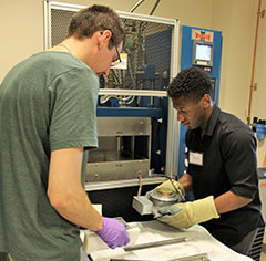 Dr. Matt Jackson, left, walks Damon Scott through the process of hot embossing microfluidic chips with PMMA.