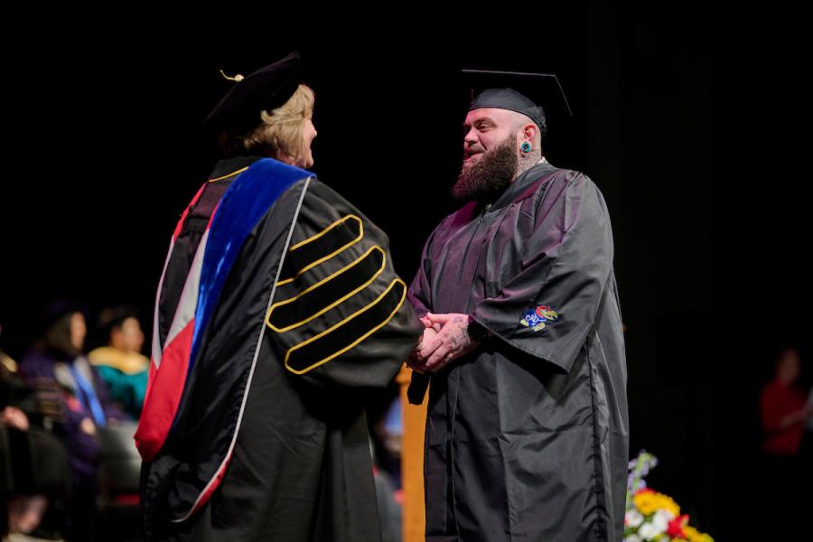 Sean Kirk shakes Dean Michelle Carney's hand at BSW graduation in Lawrence.