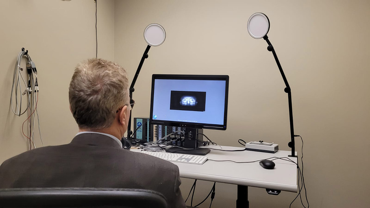 A photo showing a subject using lab equipment that tracks eye movement when looking at online content.