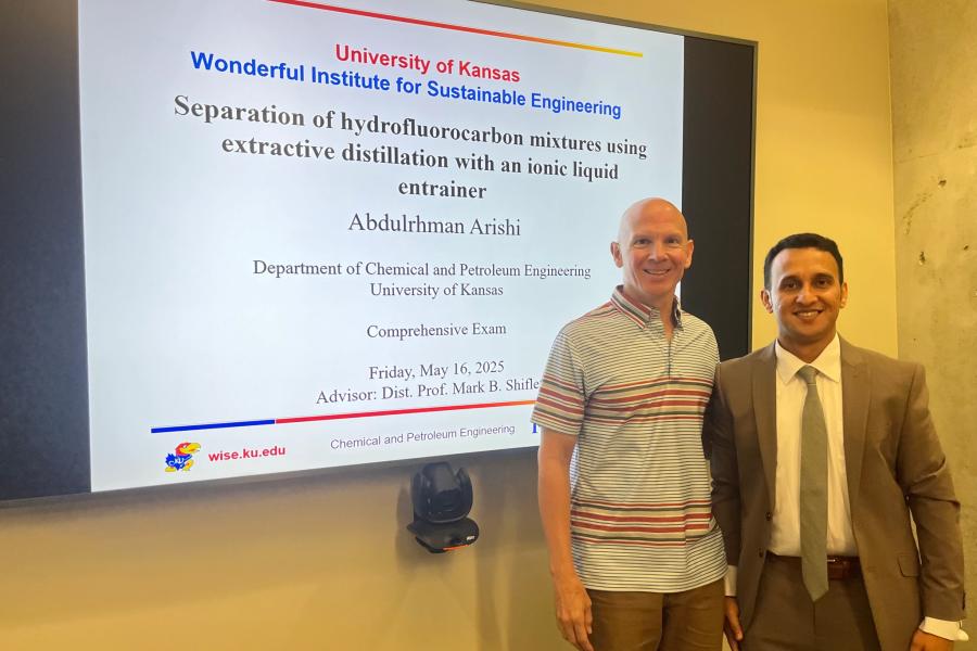 Two people posing for a photo in front of a presentation screen