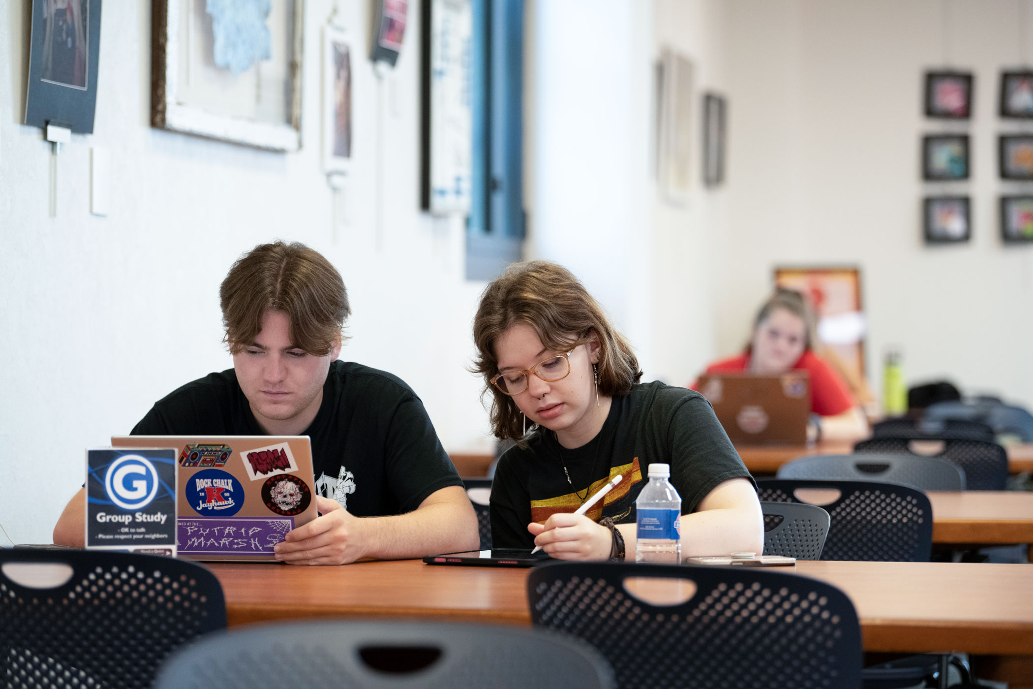 Two students accessing electronic materials from their devices in Watson Library.