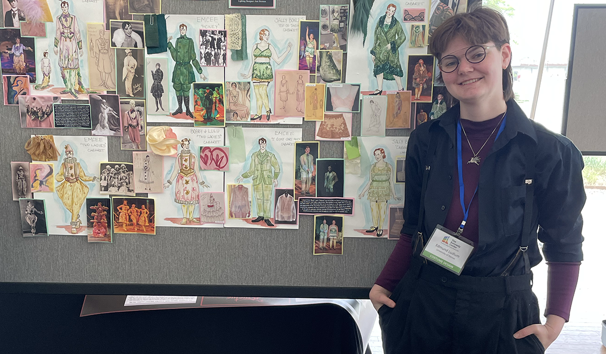 Edmund Ludlum in front of poster display featuring costume design work for a KU Theatre production of "Cabaret."