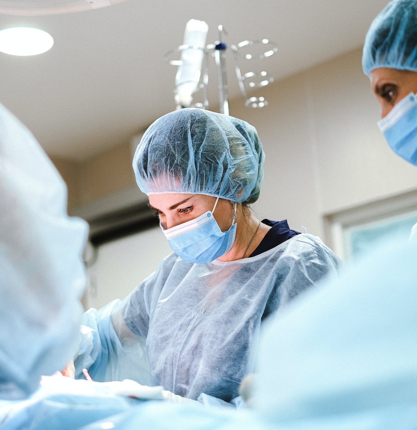 Women physician in scrubs, mask in OR.