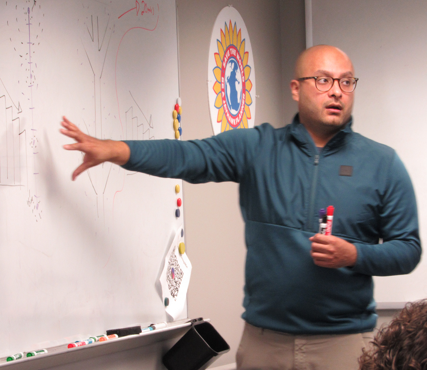 Joel Mendez stands next to whiteboard, pointing at a drawing