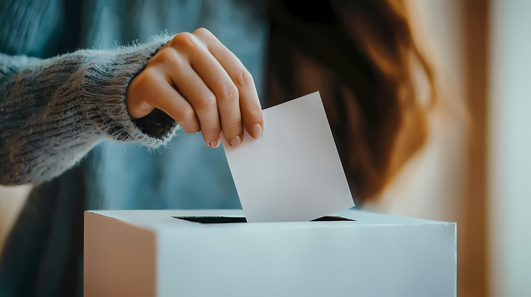 A woman places a ballot in a ballot box.