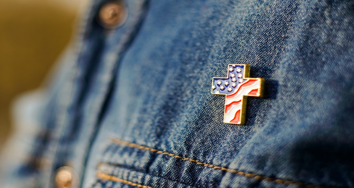 A person wearing a cross pin that features a pattern of the American flag.