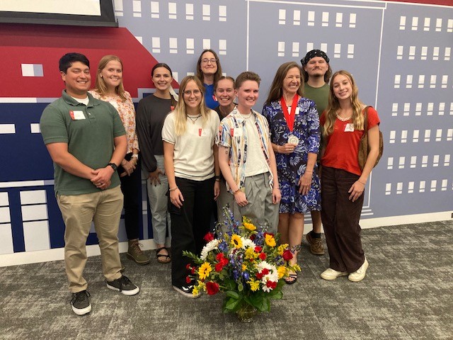 Group of students and Shannon O'Lear. Shannon is wearing award medal and smiling. 