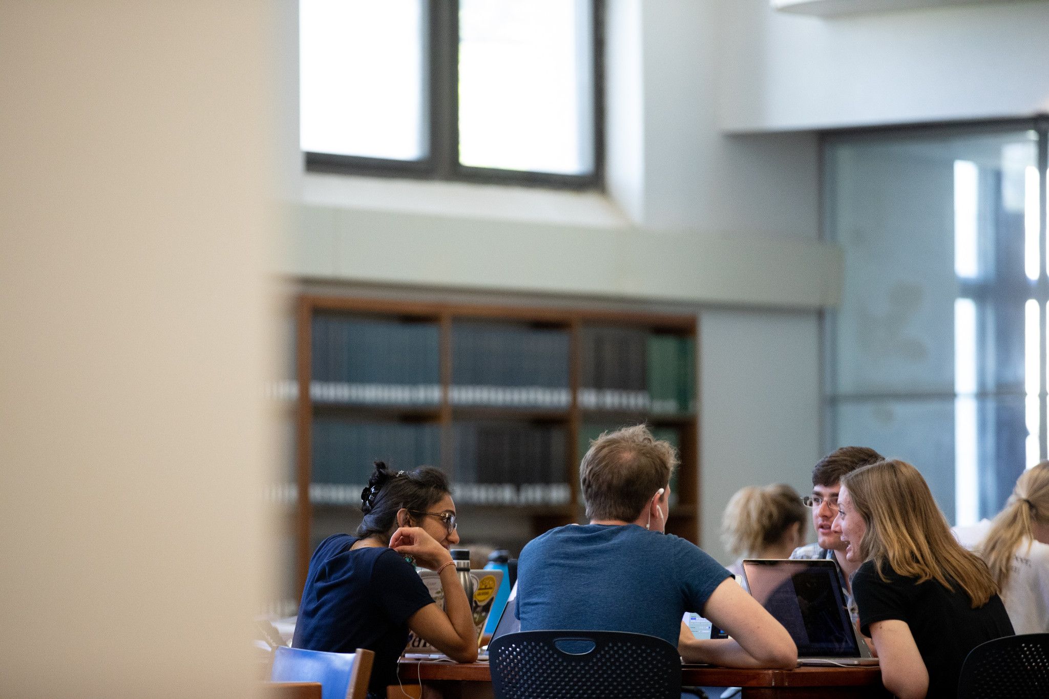 Students study at a group study table inside Watson Library.