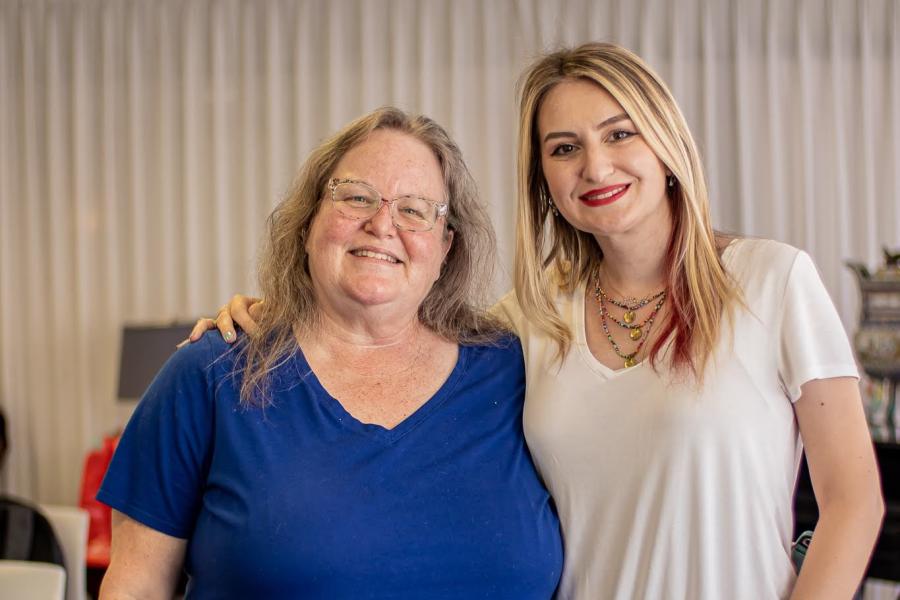 Two women standing close together, one arm each around the other.