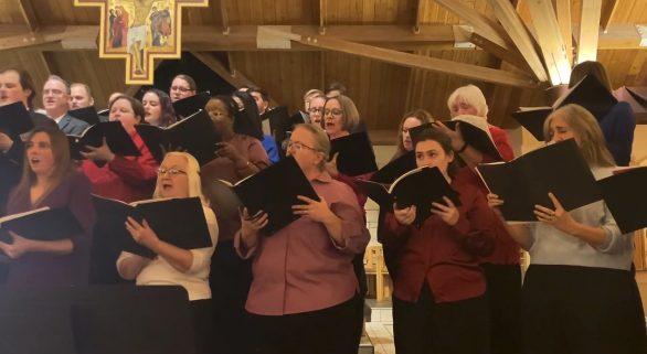 Singers holding songbooks perform for audience.