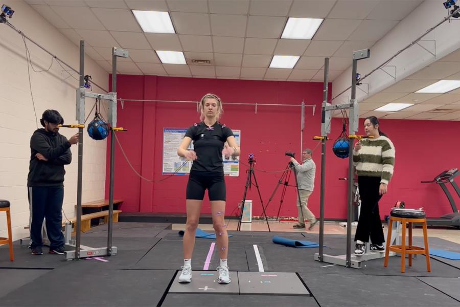 A test subject prepares to jump from a force plate while research assistants look on.