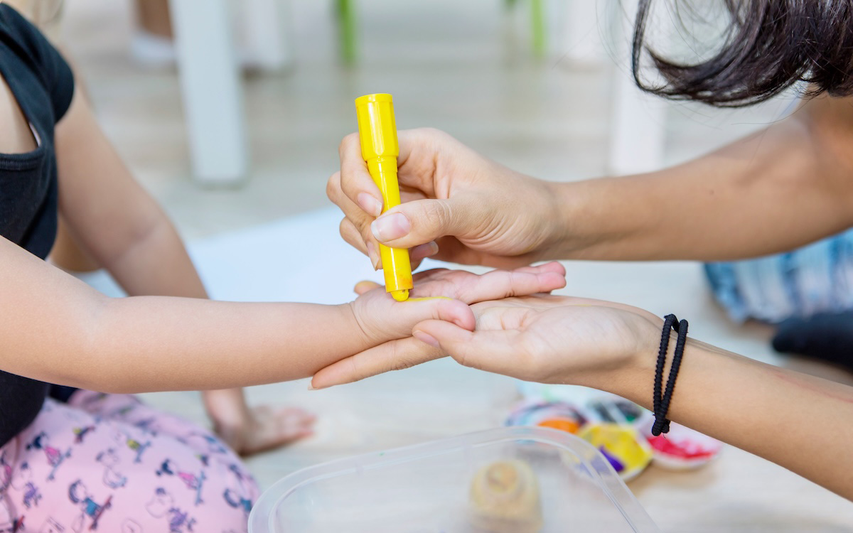 Chid and caregiver's hands in daycare setting.