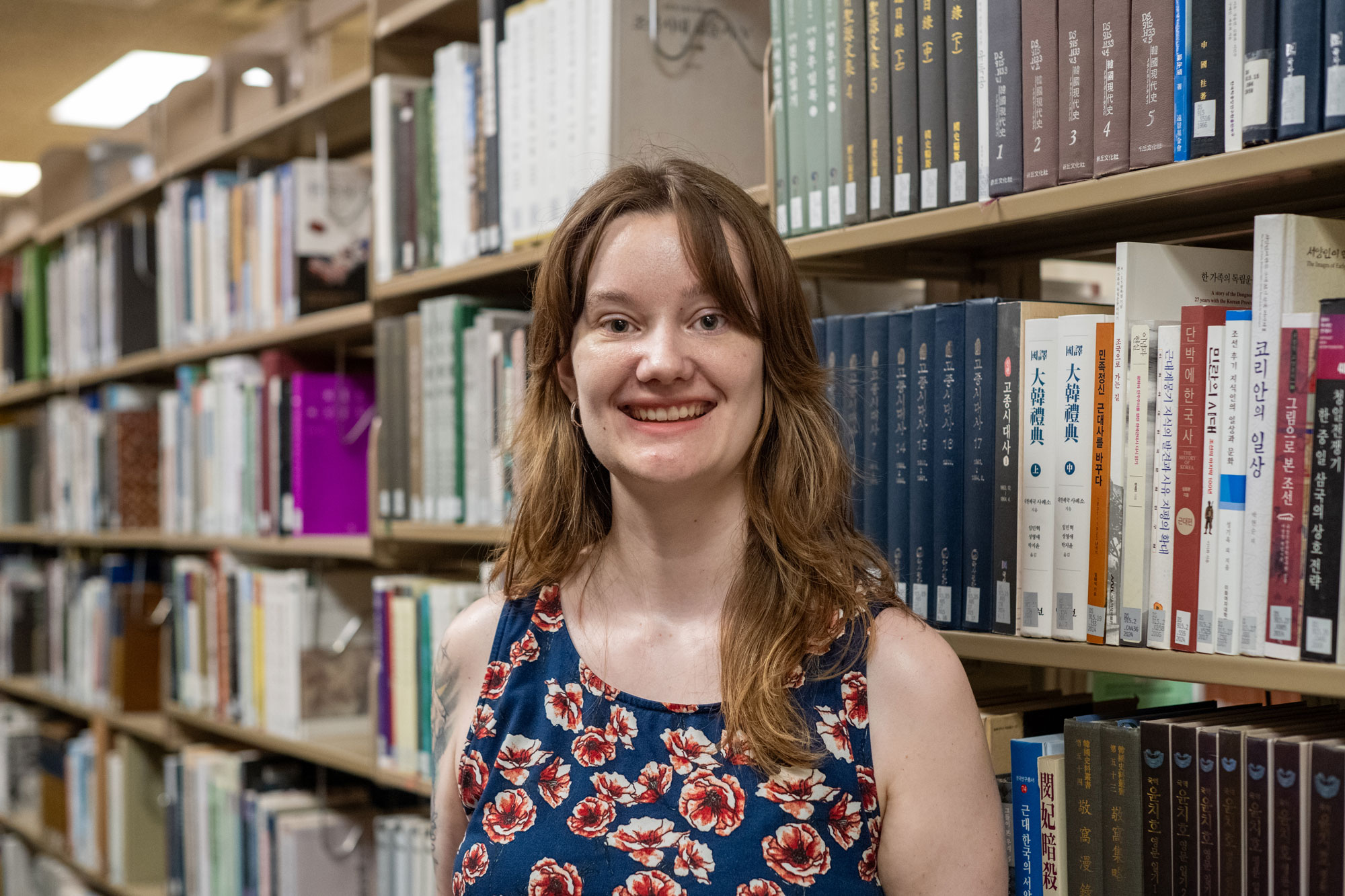 Daphne Tibbetts stands in front of a row of books.