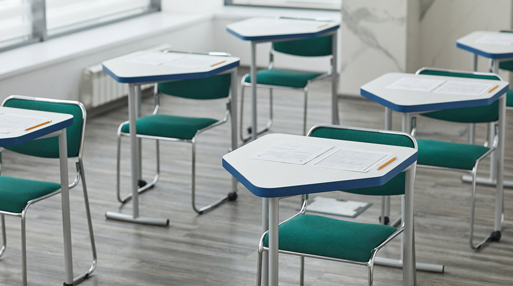 Classroom desks with tests on them. Pexels image.
