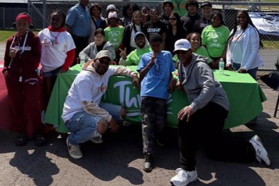 ThrYve youth, staff, police chief, and mayor in a group photo in front of Thryve table at the peace walk luncheon
