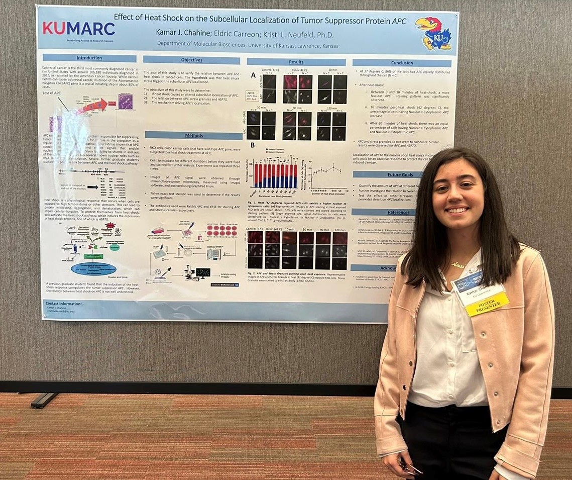 Kamar at a conference standing in front of her research poster