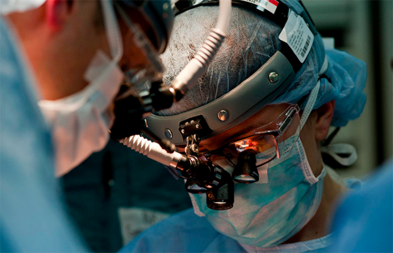 A surgeon looks through a magnifying lens during an operation