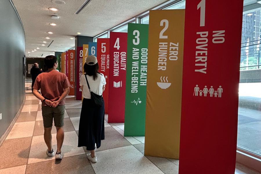 People walk down hallway past multicolored vertical posters