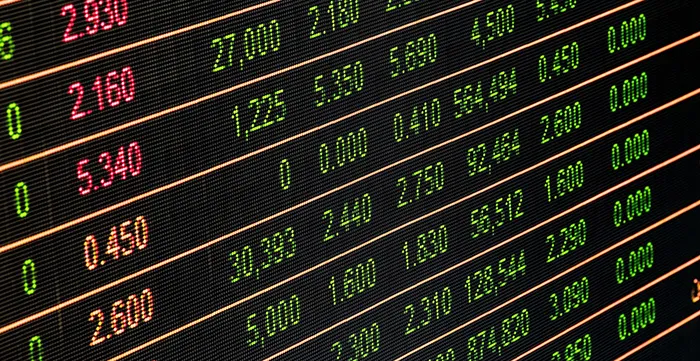 Close-up view of a stock market display board showing various stock prices in green and orange digital numbers.