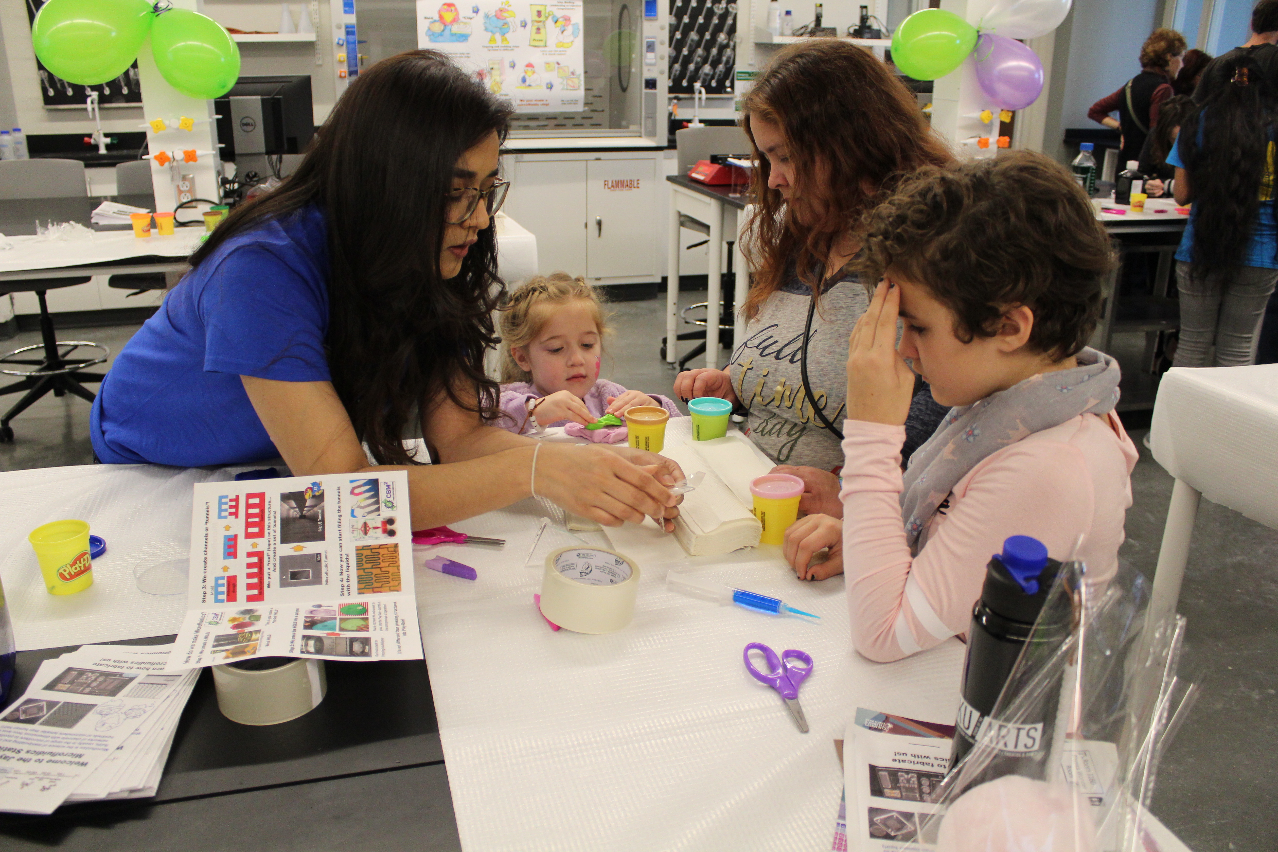 An assistant guiding a family through a craft activity.