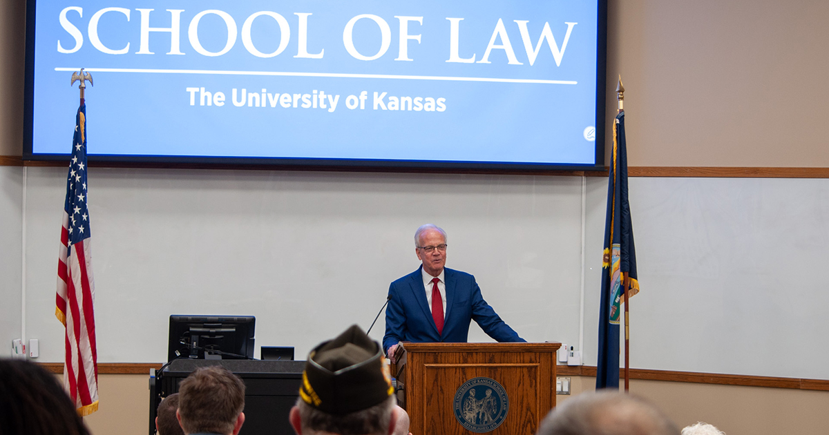 Jerry Moran making presentation at KU Law School with KU Law signage on screen behind him.