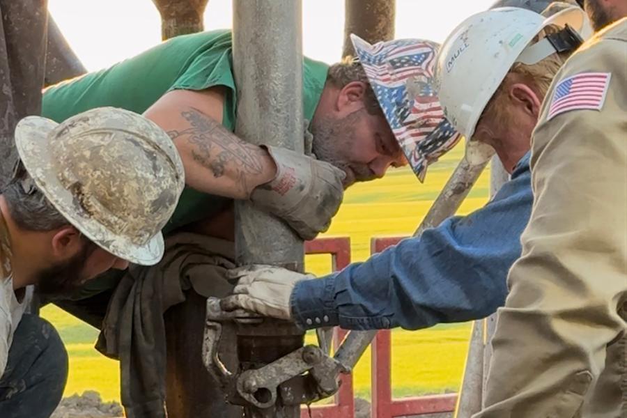 Crew members in hard hats and safety vests from Lighthouse Drilling, Kudu Coring, Mull Companies and the Kansas Geological Survey extract core from the Lyon County well.