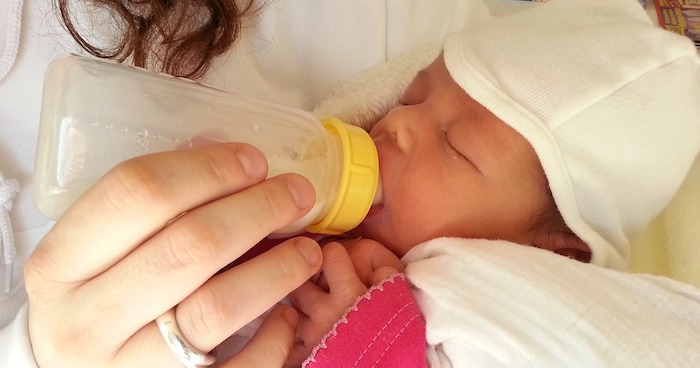 Infant being fed from bottle.