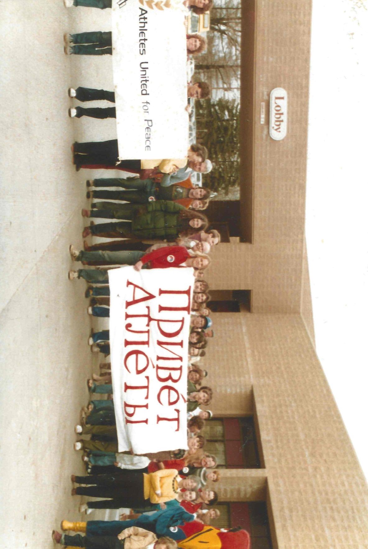Lawrence residents greet Soviet athletes arriving to participate in the Kansas Relays, April 1983. The Russian sign reads “Hello Athletes.” Courtesy of Robert Swan Jr.