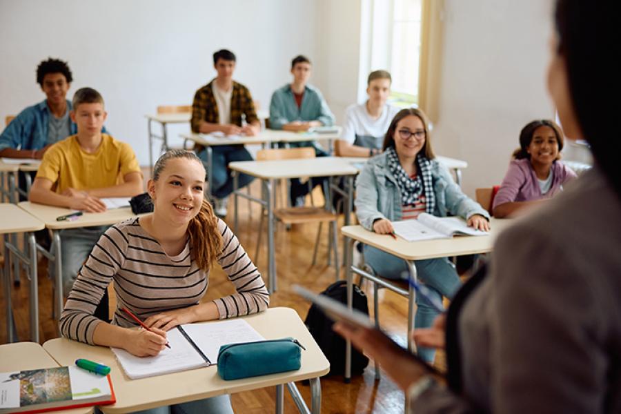 High school students sitting in a classroom and looking at their teacher.