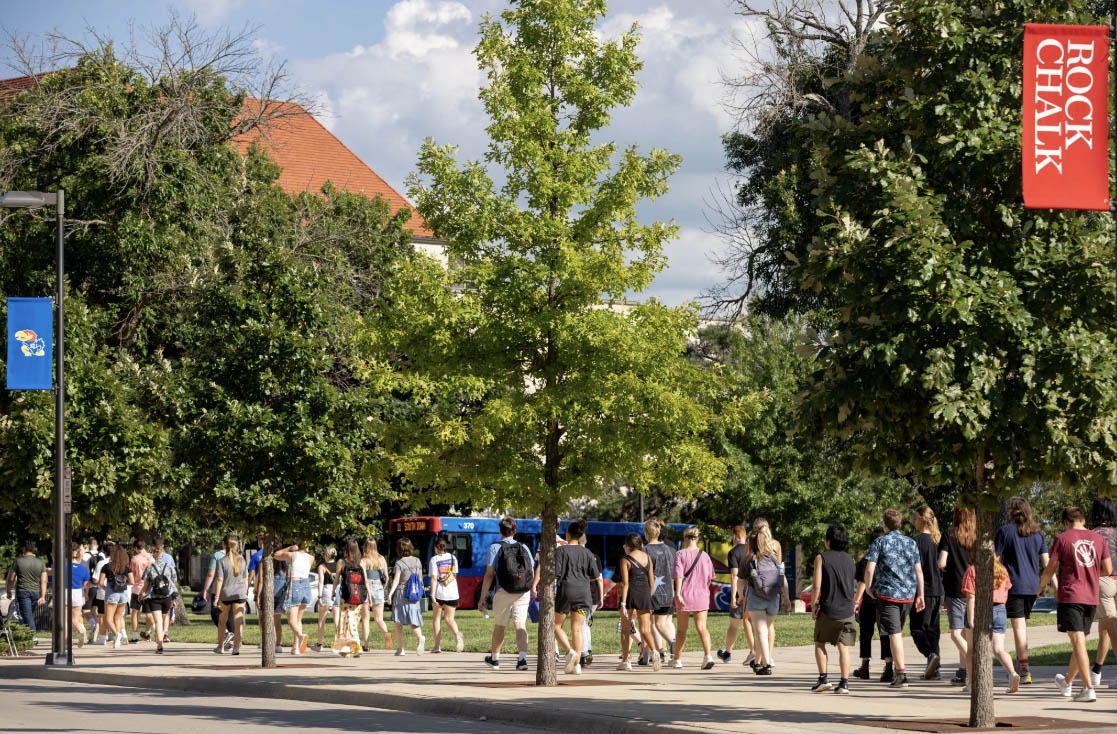 University of Kansas students carrying backpacks walk along Jayhawk Boulevard in early fall at Lawrence campus.
