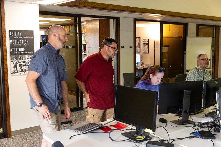 Several members of ATS's team watch computer screens.