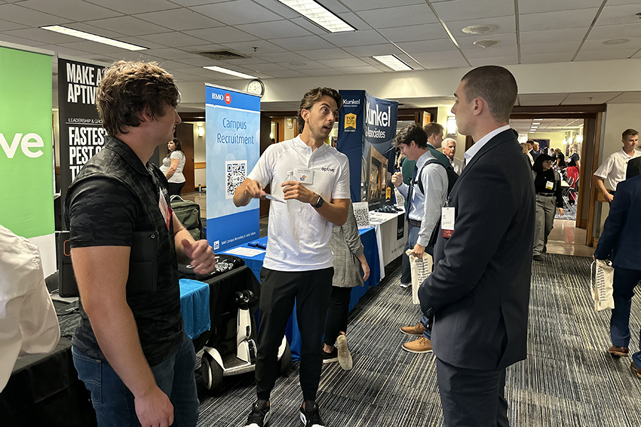 Three men talk to another during a career fair.