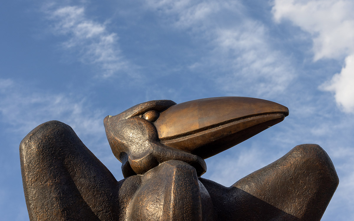 Bronze Jayhawk statue and clouds.