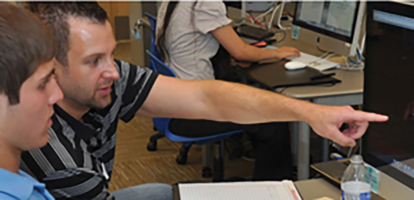 "Teacher helping student on a computer"