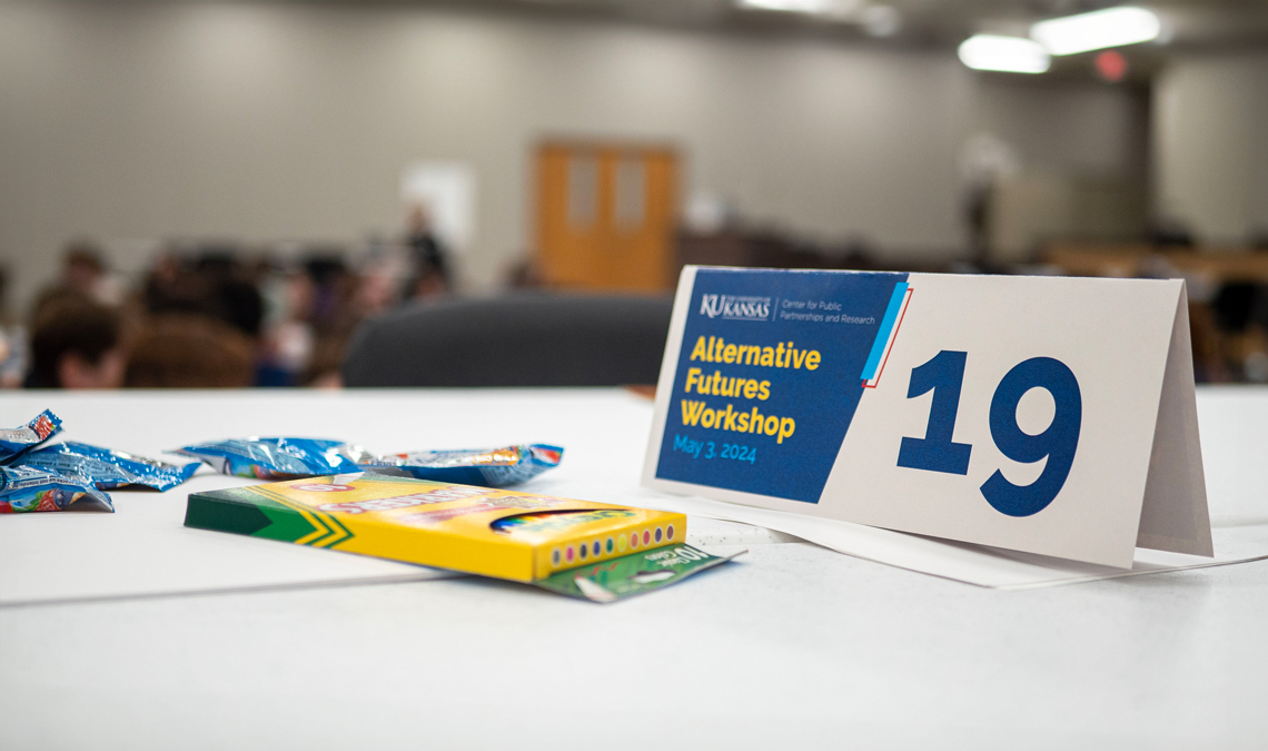 A place card with the Alternative Futures logo and a box of coloring markers on a desk