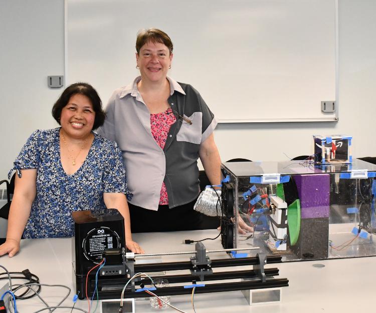 Two teachers smiling with a table of equipment in front of them