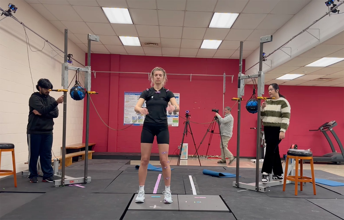 A test subject prepares to jump from a force plate while research assistants look on.