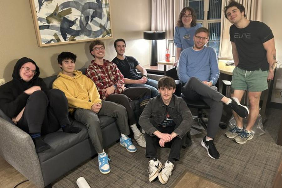 KU debaters standing and seated around couch in small room in Washington, D.C.