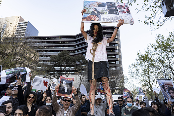 A woman holds a sign and wears a noose during solidarity protests in Melbourne, Australia. The protests were in conjunction with the Iranian women's movement following the death of Mahsa Jina Amini. Credit: Wikimedia Commons.