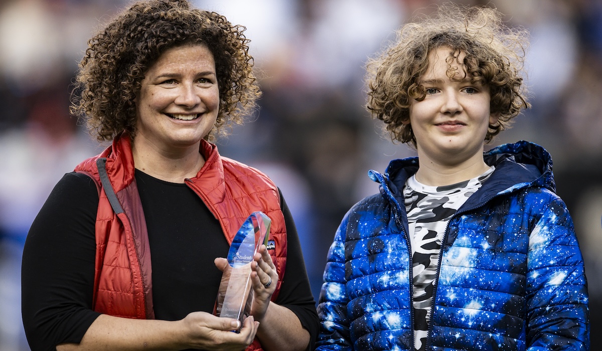 Betsy Barnhart, holding HOPE Award, and her son Sam on the football field