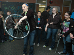 Group of students, one with bicycle wheel.