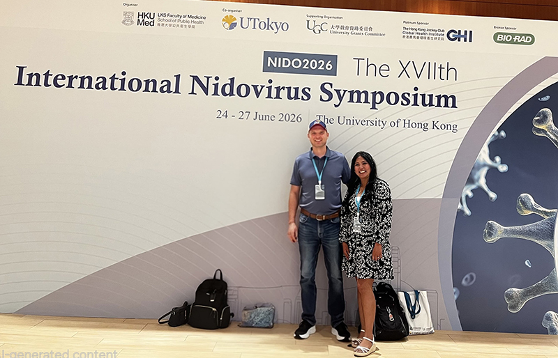 Pradtahna Saenjamsai stands with Dr. Tony Fehr in front of International Nidovirus Symposium backdrop
