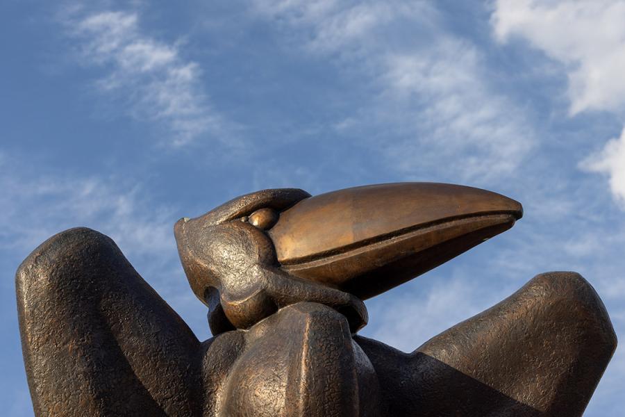 Bronze Jayhawk statue and clouds.