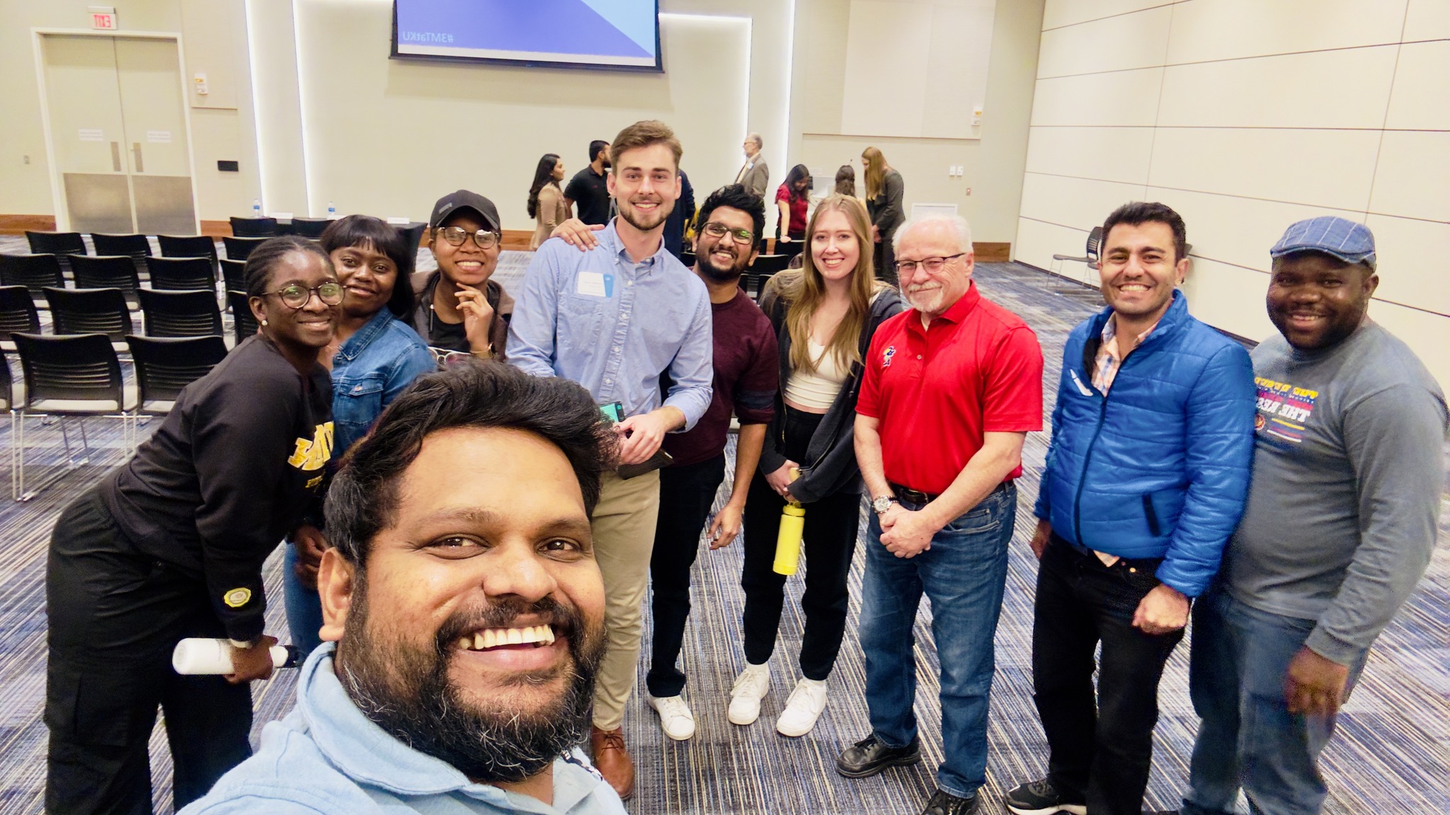 A group of CBM2 team members gathered at a convention, smiling and posing for a picture.