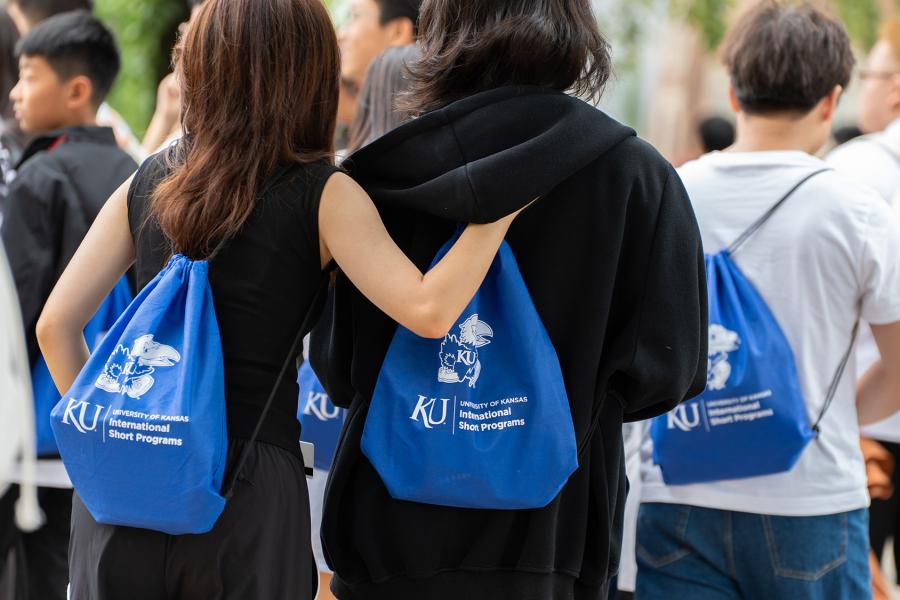 Two students stand next to each other wearing KU International Short Programs bag.