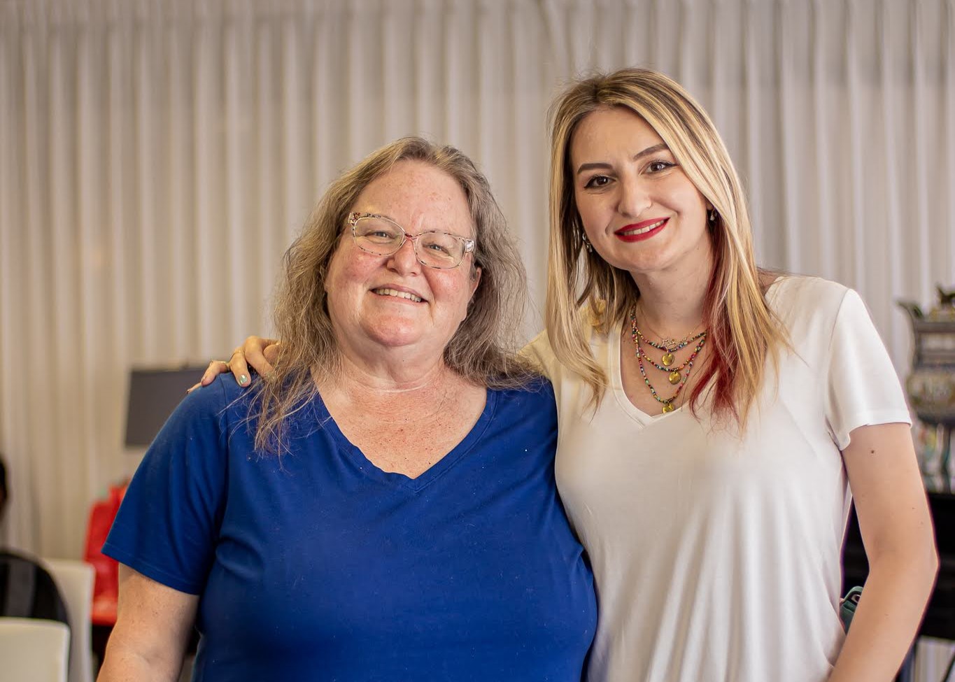 Two women standing close together, one arm each around the other.