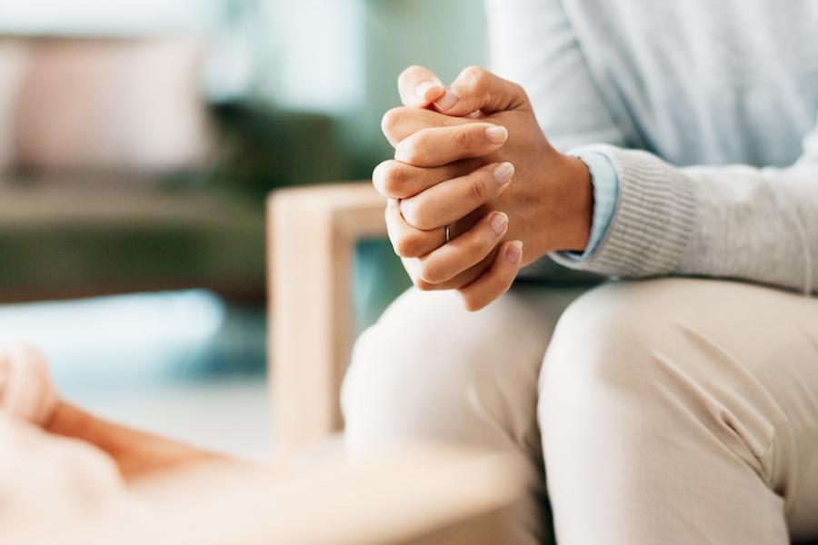 Stock photo of woman's hands with psychologist in consultation office for assessment or evaluation.